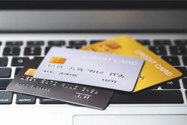 Cartão de crédito colorido sobre teclado de notebook, representando compras online e pagamentos digitais.