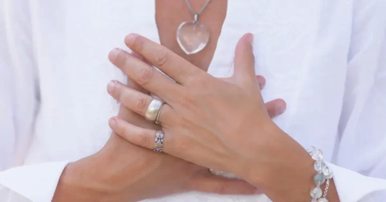 Mãos cruzadas sobre o peito em gesto de autocuidado, simbolizando como melhorar a autoestima e fortalecer o amor próprio.