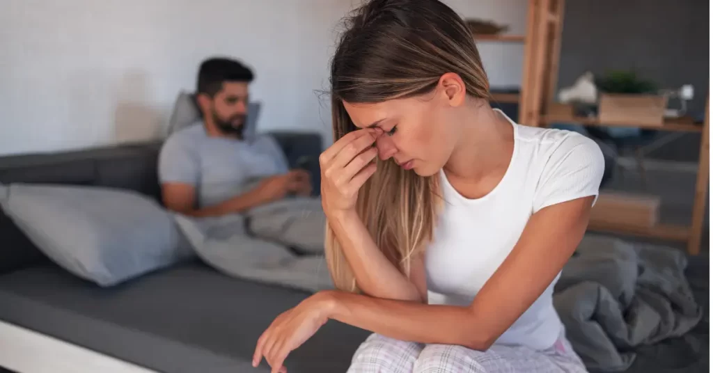 Cena de casal distante, com mulher angustiada, representando sinais de um relacionamento tóxico.