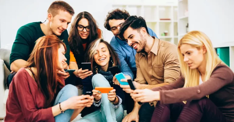 Grupo de jovens usando smartphones e interagindo nas redes sociais em 2026 de forma natural e descontraída